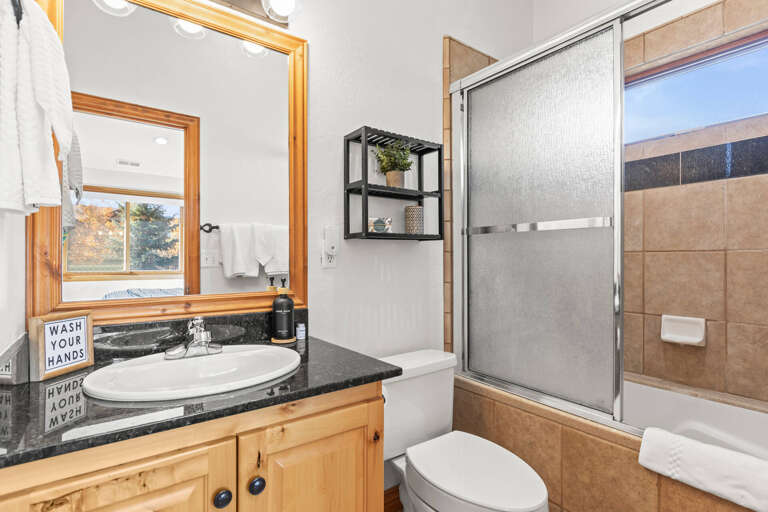 Step into your private bathroom with warm wood tones, granite countertops, and a relaxing shower-tub combo—freshly stocked towels await.