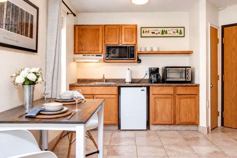 Your cozy kitchenette awaits with everything you need to prepare light meals—microwave, toaster oven, coffee maker, and mini fridge. Gather at the welcoming dining table and enjoy the charming alpine artwork that adds a warm, mountain-retreat feel.