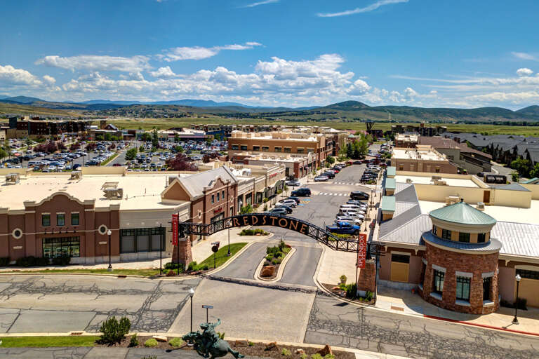 Aerial view of the surrounding shopping and dining district, with mountain vistas defining the horizon and convenient access to local amenities.