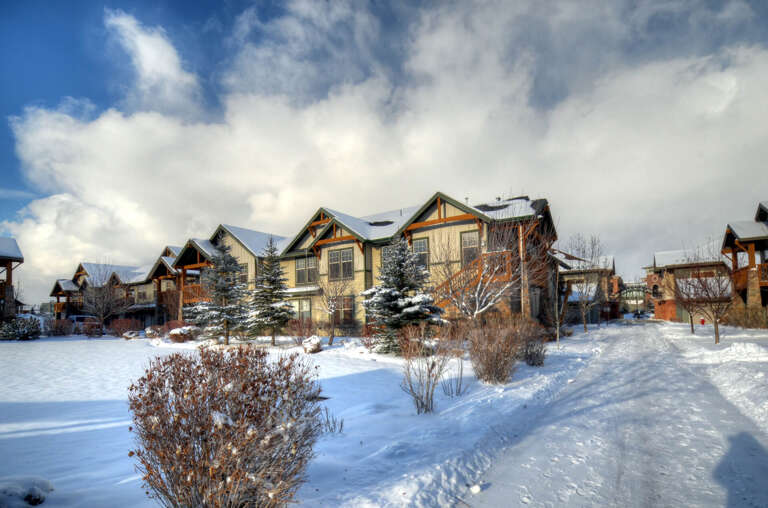 Snow-dusted alpine condominiums nestled among evergreens offer a classic mountain retreat surrounded by pristine winter scenery and peaceful neighborhood charm.