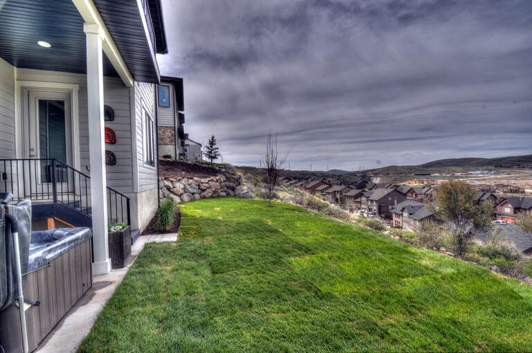 Elevated property nestled on a hillside offering sweeping views of the surrounding neighborhood and mountain landscape, with convenient outdoor hot tub access.