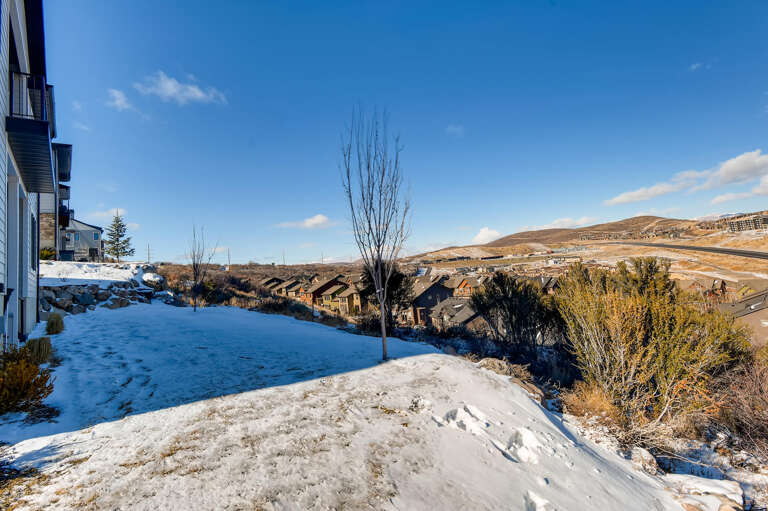 Expansive mountain views stretch across rolling hills and nearby residential areas, capturing the scenic neighborhood setting in winter sunlight.