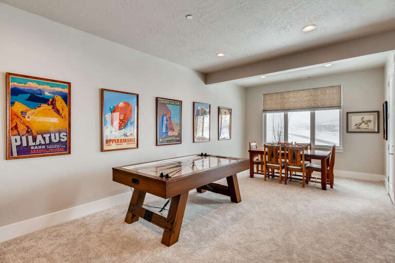 Your game room awaits with a classic foosball table, cozy dining nook by the window, and vintage ski posters setting the perfect après-ski vibe.