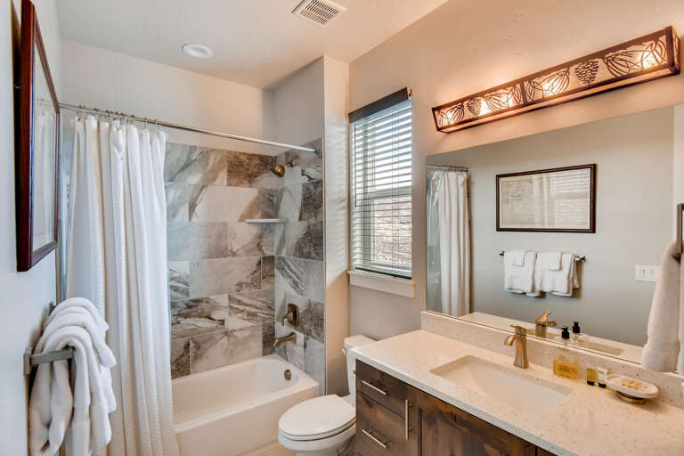 Jordanelle Estates 13299: Sleek sink, mirror, toilet, and convenient tub shower combo.