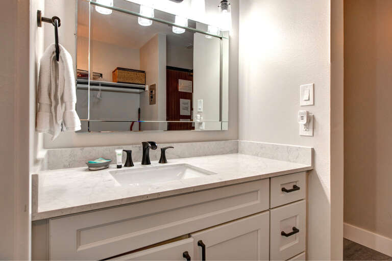 Sleek sink, mirror, cabinets, and overhead lights create a cozy space. Sleek sink, mirror, cabinets, and overhead lights create a cozy space.