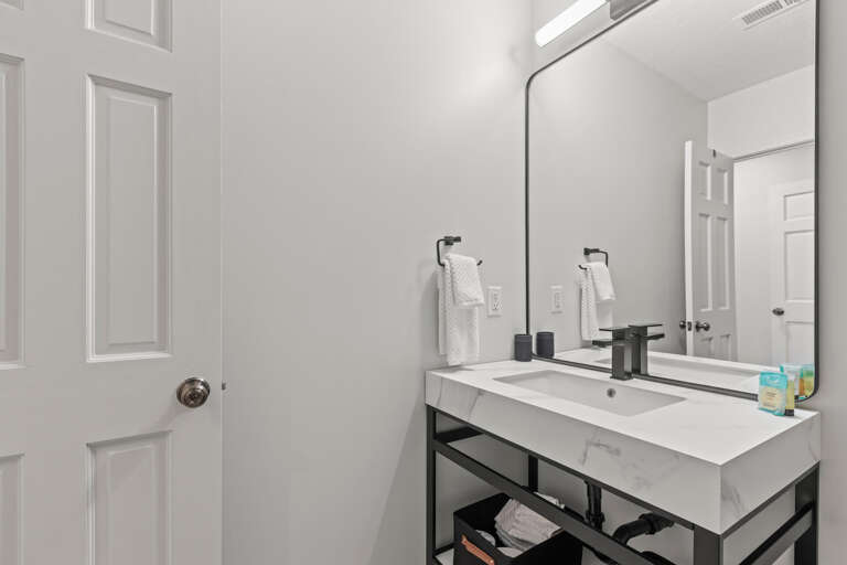 Step into your sleek, modern bathroom with crisp white marble counters, matte black fixtures, and fresh towels waiting. The frameless mirror amplifies the bright, clean space—perfect for your morning routine.