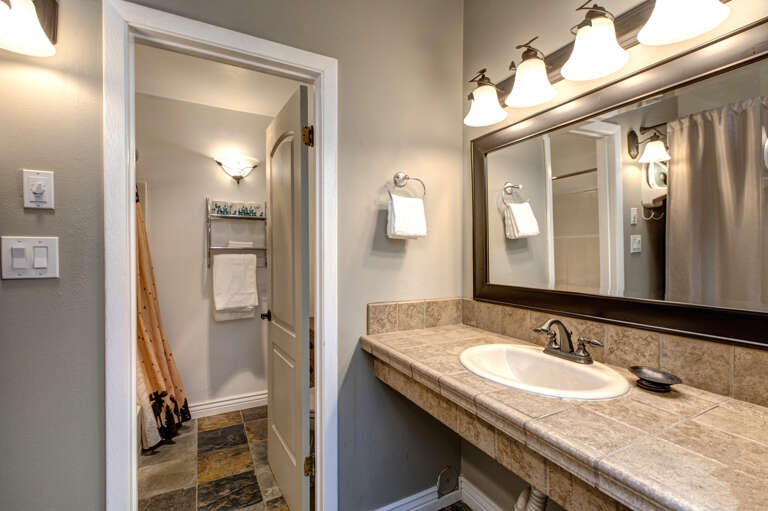Beige-themed sink area with mirror and overhead lights. Beige-themed sink area with mirror and overhead lights.