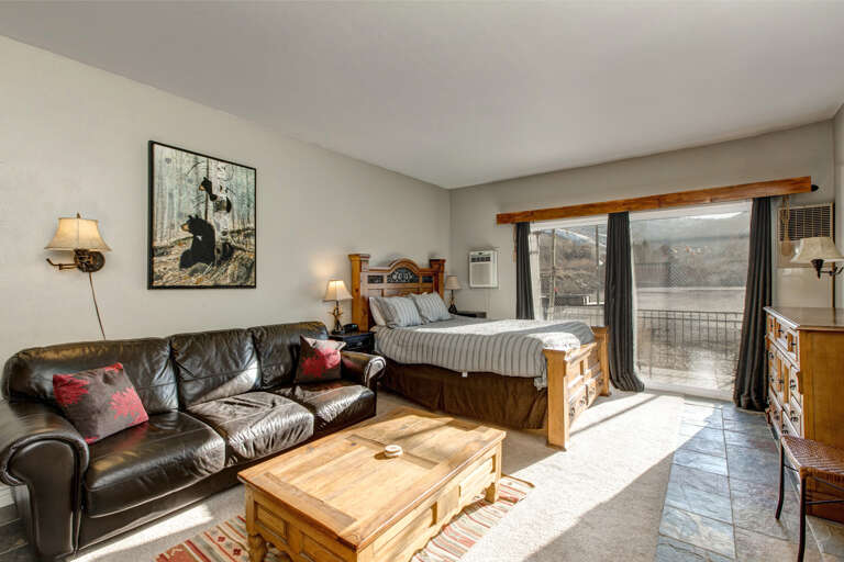 Cozy studio with queen bed, sofa, TV, and outdoor patio view. Cozy studio with queen bed, sofa, TV, and outdoor patio view.