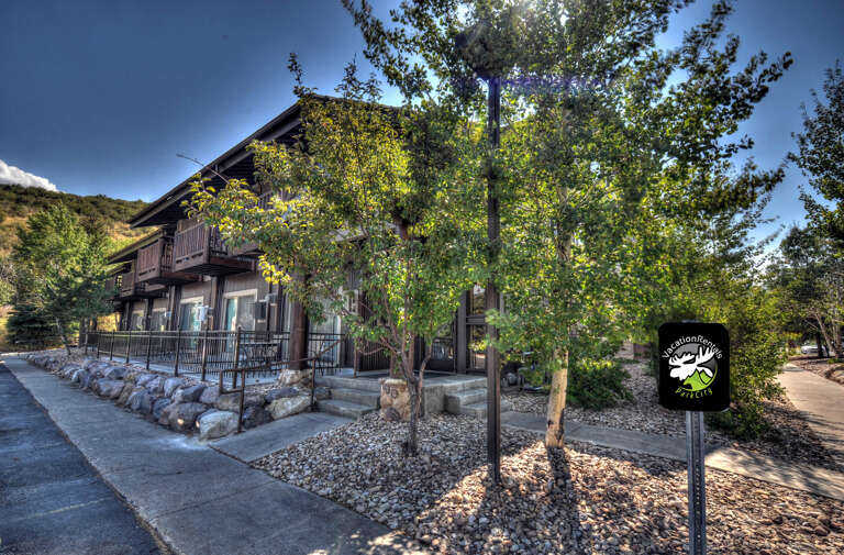 Nestled among trees and hillside views, the property's entrance sets a welcoming mountain-retreat tone.