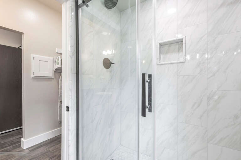 Sleek glass shower in a bright white tiled enclosure. Sleek glass shower in a bright white tiled enclosure.