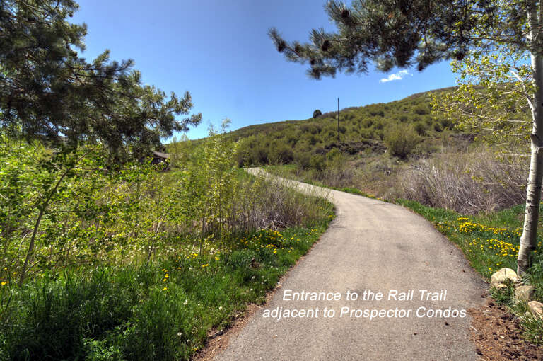 A scenic rail trail entrance near the property offers easy access to hiking paths through natural hillside terrain with wildflowers and mountain views.