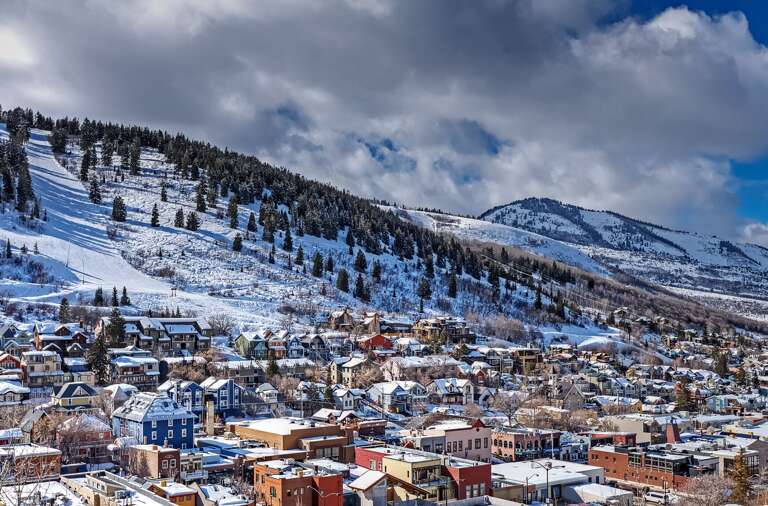 A charming mountain town nestled beneath snow-covered peaks, offering a picturesque winter setting surrounded by nature's majesty.