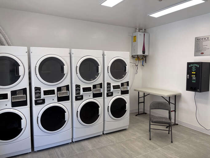 A convenient shared laundry facility with multiple washers and dryers, a folding table, and seating to make laundry day easier during your stay.