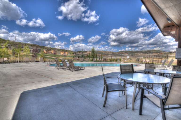 A sparkling pool surrounded by rolling hills under a dramatic sky—perfect for relaxing after exploring the beautiful desert landscape nearby.