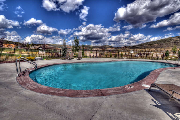 Sparkling outdoor pool surrounded by rolling hills and dramatic skies—a perfect spot to unwind after exploring the area.