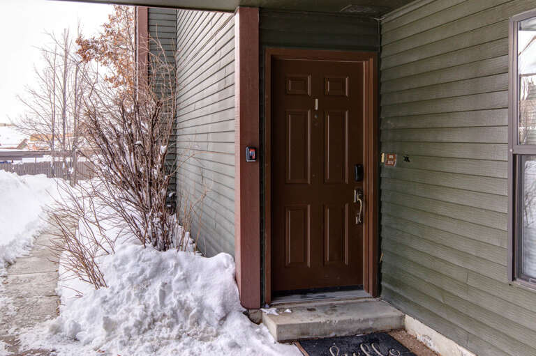 The main entrance welcomes you to your winter getaway, framed by peaceful snow-covered surroundings and a private, sheltered entryway for your arrival.