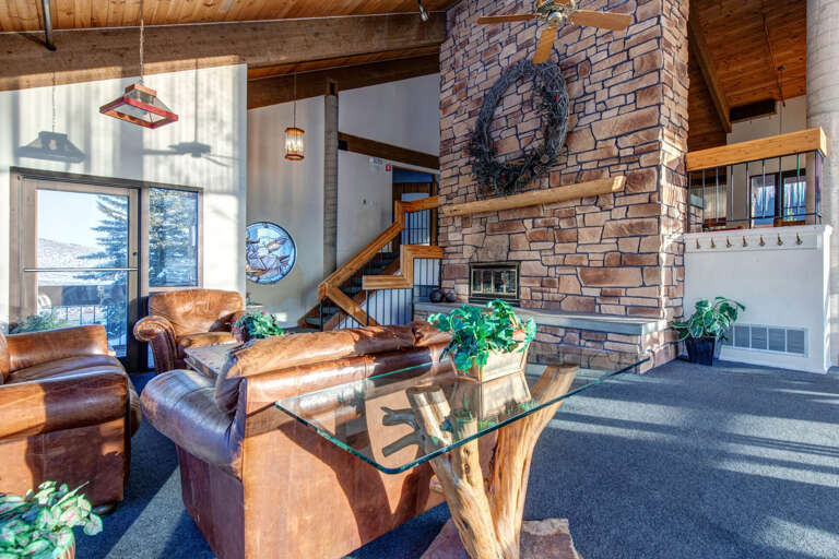 Sink into rich leather seating by the stone fireplace, where vaulted wood ceilings and sunlit windows create your warm mountain retreat.