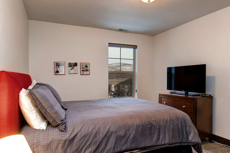 Relax in your cozy bedroom with plush linens, a flat-screen TV, and stunning mountain views framing your peaceful retreat.