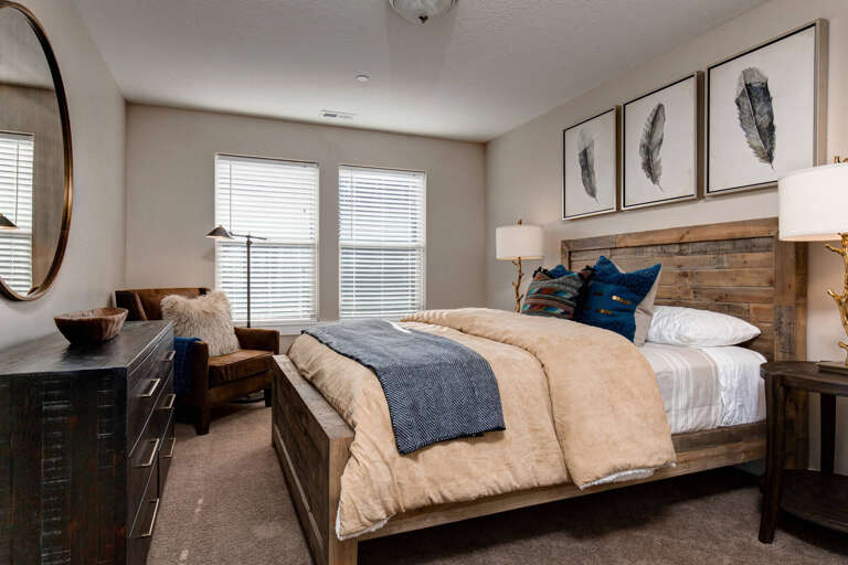 Sink into plush bedding and rustic wood accents in your serene bedroom retreat, where natural light streams through large windows, inviting peaceful rest after a day of adventure.