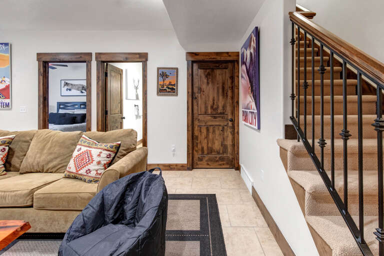 Your downstairs living area invites you to unwind on cozy sofas, with vintage ski posters adding alpine charm and bedrooms just steps away for easy access.