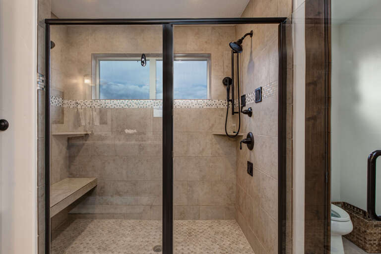 Step into your spacious walk-in shower with dual showerheads, a built-in bench, and elegant tile work designed for your comfort and relaxation.