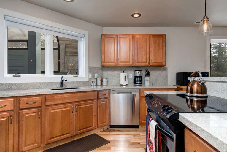 Prepare your favorite meals in this fully equipped kitchen with stainless steel appliances, granite countertops, and warm wood cabinetry providing ample storage for all your culinary needs.