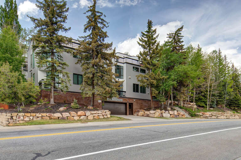 Modern mountain retreat nestled among tall pines and aspens, featuring brick and contemporary architecture along a quiet tree-lined street.