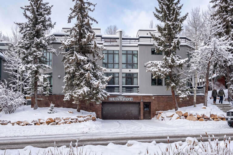 The Sunspot property stands nestled among snow-laden evergreens, offering a serene winter mountain retreat surrounded by pristine natural beauty and peaceful wooded grounds.