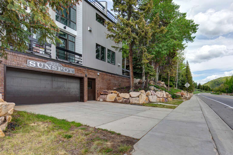 The Suncod building sits in a tree-lined neighborhood with mountain-framed views and convenient street access, marking the entrance to the property.