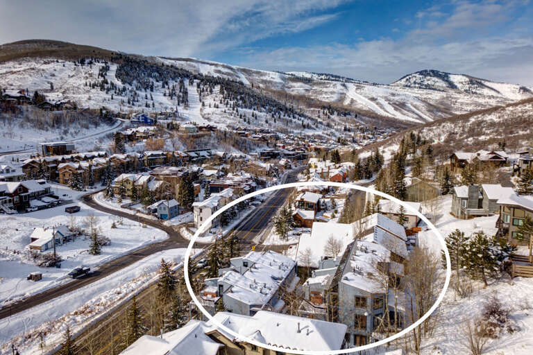 Aerial view of a charming mountain town nestled in a snowy valley, surrounded by ski slopes and natural winter beauty.