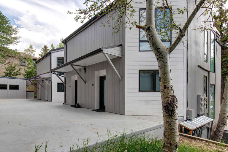Modern rental property featuring contemporary architecture with clean lines and neutral tones, set among mature trees in a peaceful residential area.