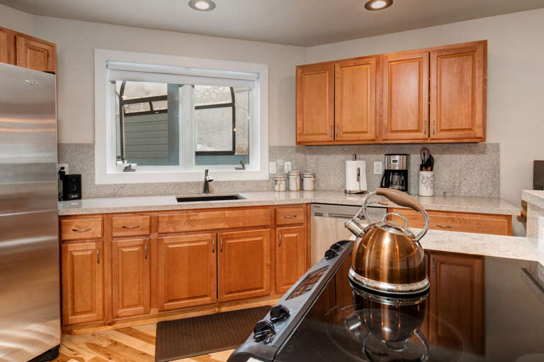 Whip up your favorite meals in this bright, fully-equipped kitchen with warm wood cabinetry, granite counters, and stainless steel appliances—everything you need for a cozy stay.