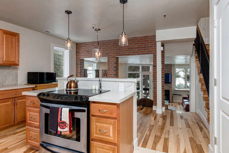 Step into your gourmet kitchen where exposed brick and warm wood tones create an inviting atmosphere. Prepare meals on granite counters under elegant pendant lighting while enjoying open sightlines throughout your home.