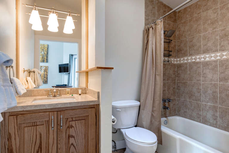Step into your private bathroom, where warm wood tones and soft lighting welcome you. Fresh towels await, and the neutral palette invites you to unwind after a day of adventure.