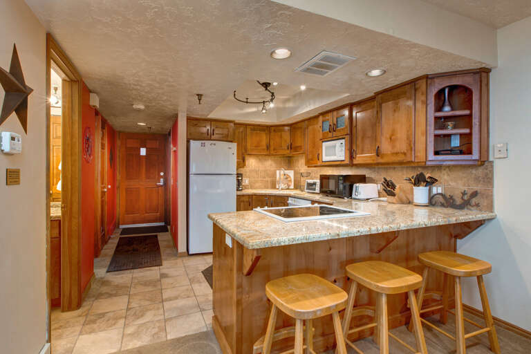 Sleek countertops, stylish bar stools, inviting hallway to cozy rooms.