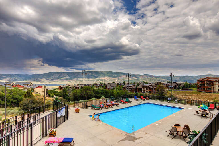 An inviting pool area offering sweeping mountain views, surrounded by sunbeds and scenic hillside vistas. Perfect for sunny afternoons and relaxation in a picturesque setting.