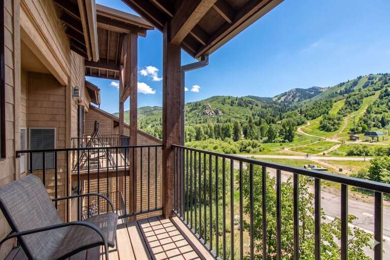 A spacious private balcony frames sweeping mountain views, green slopes, and sunny blue skiesâperfect for your morning coffee or quiet evening relaxation.