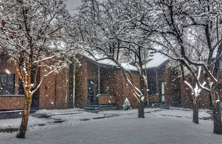 Softly falling snow blankets the property and surrounding trees, creating a serene winter retreat where you can enjoy the peaceful mountain atmosphere and natural beauty.