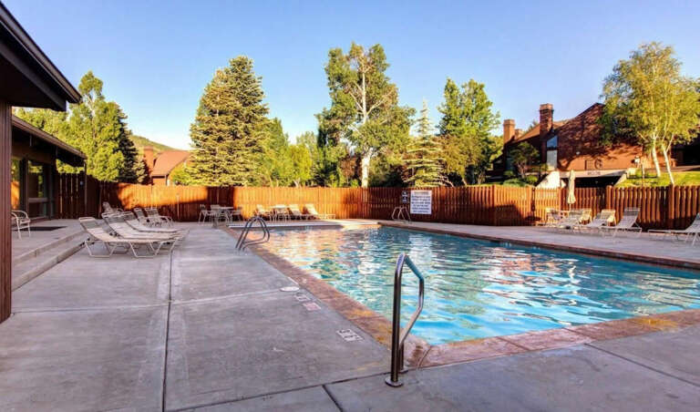 An inviting outdoor pool surrounded by mature trees and mountain views, offering a peaceful spot to relax and unwind during your mountain escape.