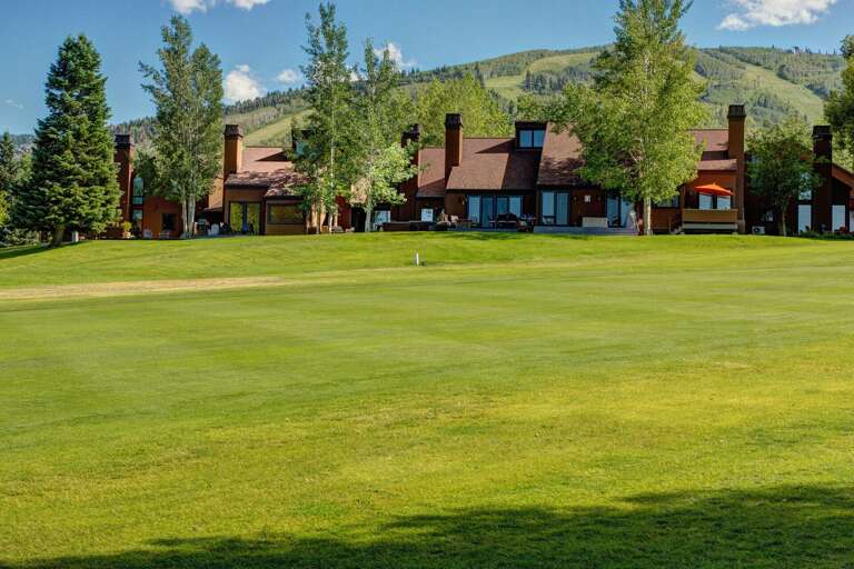 The property sits on a private golf course with scenic mountain views and mature trees framing the manicured greens, offering a serene mountain resort setting for outdoor recreation.