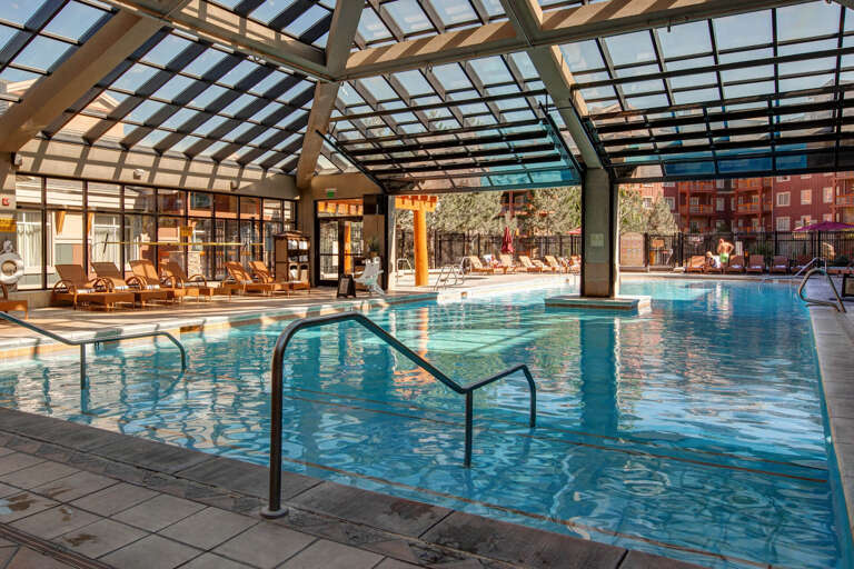 Immerse yourself in the sparkling indoor-outdoor pool, where sunlight streams through the elegant glass roof and inviting loungers await your next moment of pure relaxation.