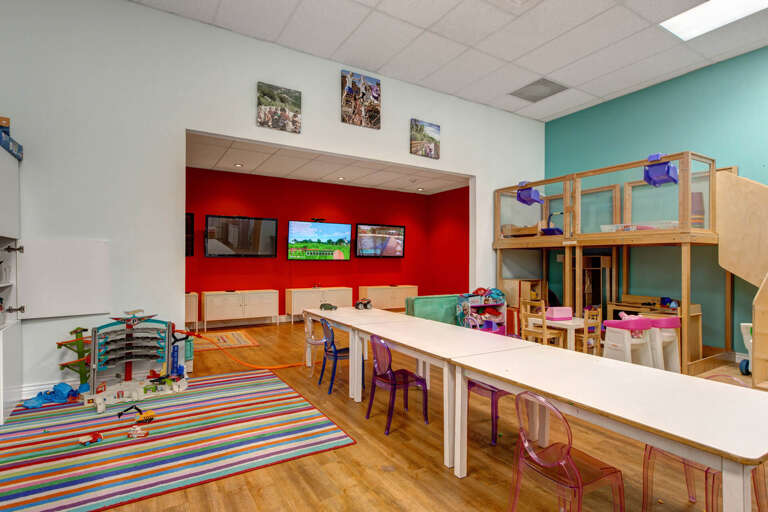 A vibrant kids' club with play structures, gaming screens, and colorful seating where your little ones can explore, create, and make new friends.