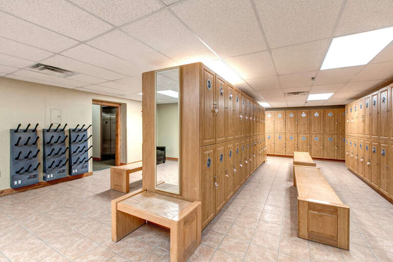 This well-organized locker room provides secure storage for your belongings with numbered lockers, a full-length mirror for convenience, and comfortable wooden benches to help you prepare for your day.