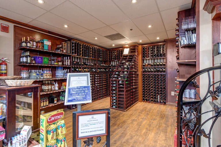 This on-site retail space features an extensive wine selection with organized displays, spirits, and convenience items. Note age restrictions apply for purchases.