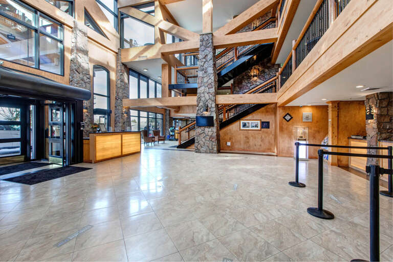 A grand lobby welcomes you with soaring timber beams, natural stone pillars, and warm wood accents that create an inviting mountain retreat atmosphere.