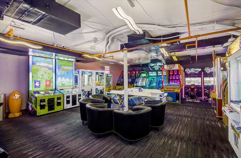 Your private game room features classic arcade machines, racing simulators, and plush seating—perfect for friendly competition and hours of fun with family or friends.