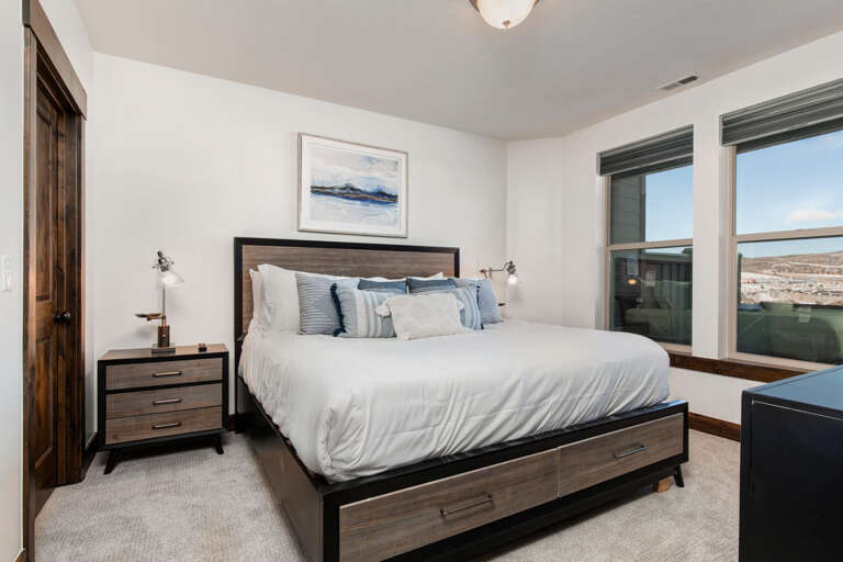 Drift off to restful sleep in this inviting bedroom, where coastal artwork sets a tranquil tone and wide windows frame scenic desert views. Plush bedding and thoughtful touches ensure your comfort.