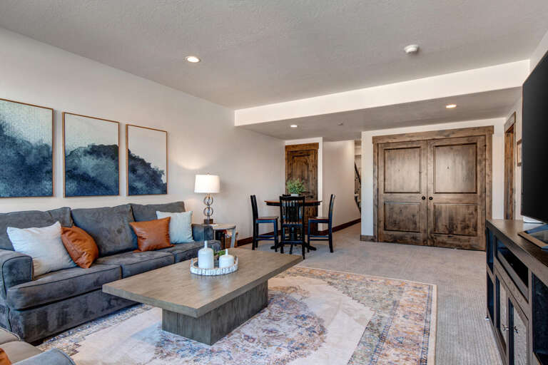 Sink into the plush sofa and unwind in your spacious living area, where rustic charm meets modern comfort with warm wood accents and soothing coastal-inspired artwork.