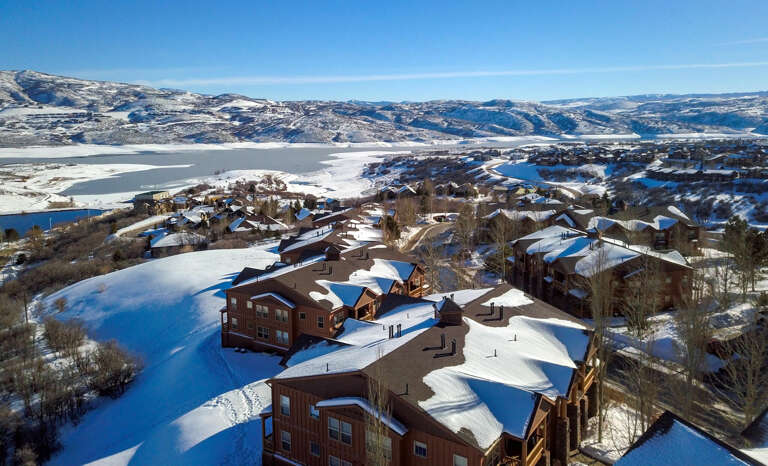 Aerial view of the vacation rental property nestled in a scenic winter landscape, with snow-covered mountains and a frozen lake framing this peaceful mountain community.