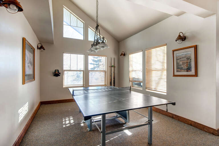 Challenge your friends to a game of ping pong in this bright, vaulted-ceiling game room with rustic-chic lighting and mountain views through the windows.